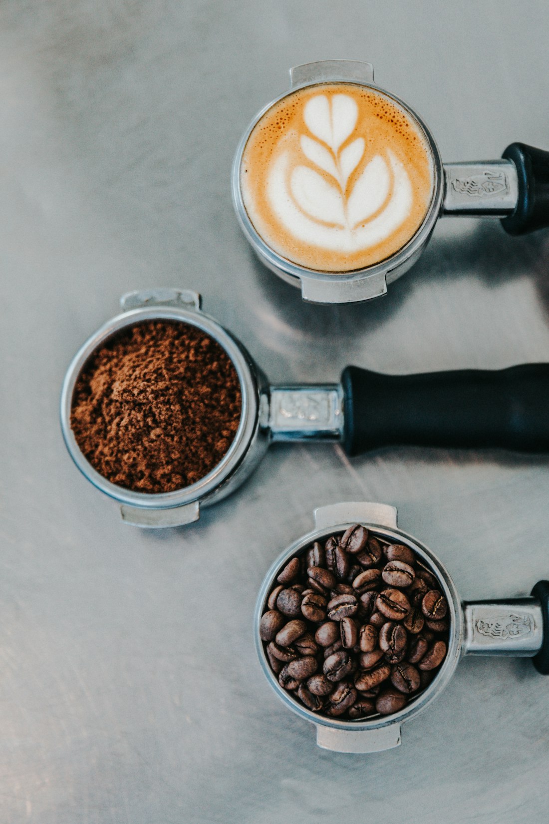 Portafilters with latte art, ground coffee and beans