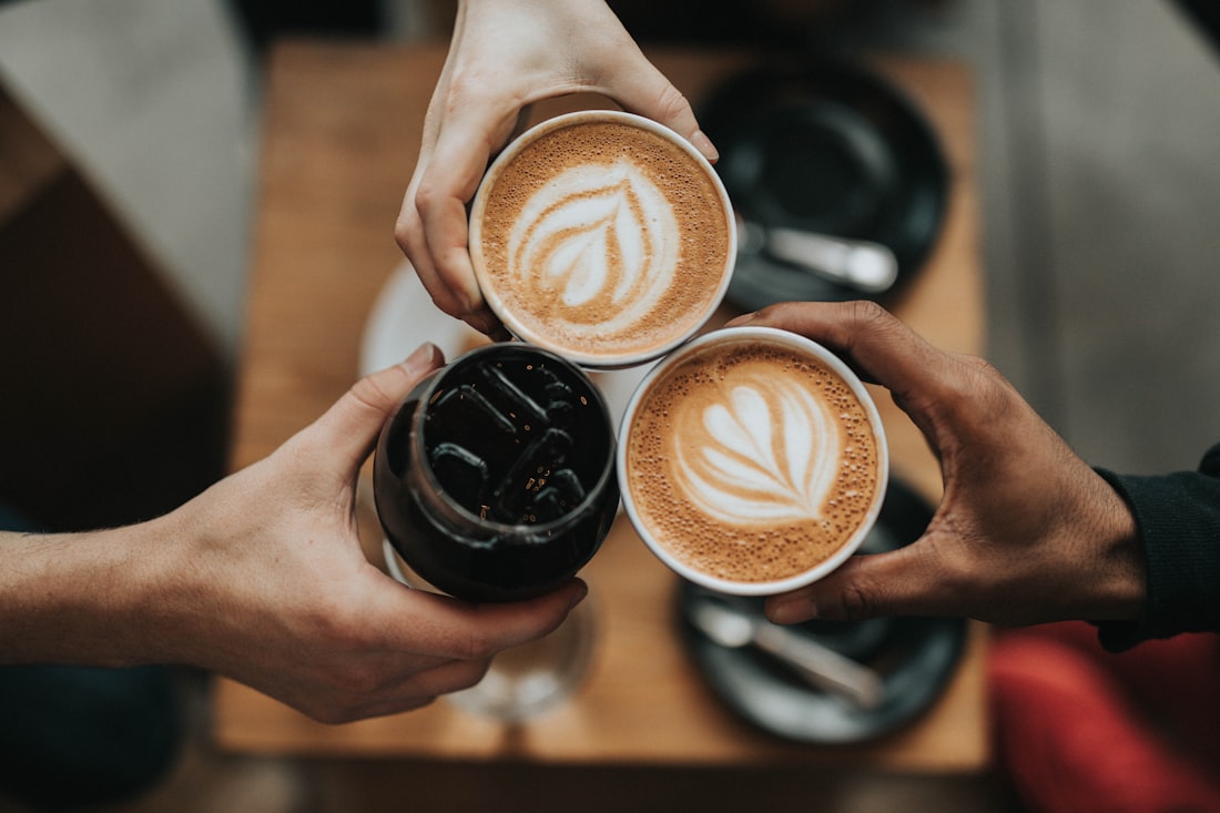 Hands raising coffee cups together